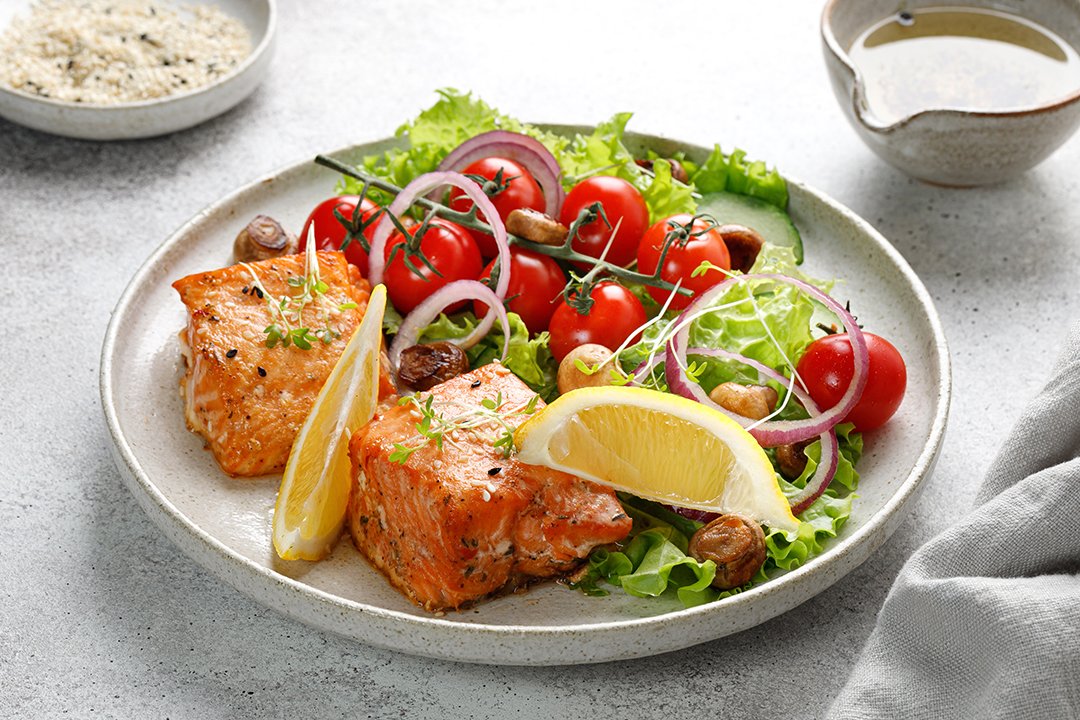 Dish with baked Salmon steak fillet with fresh green salad with